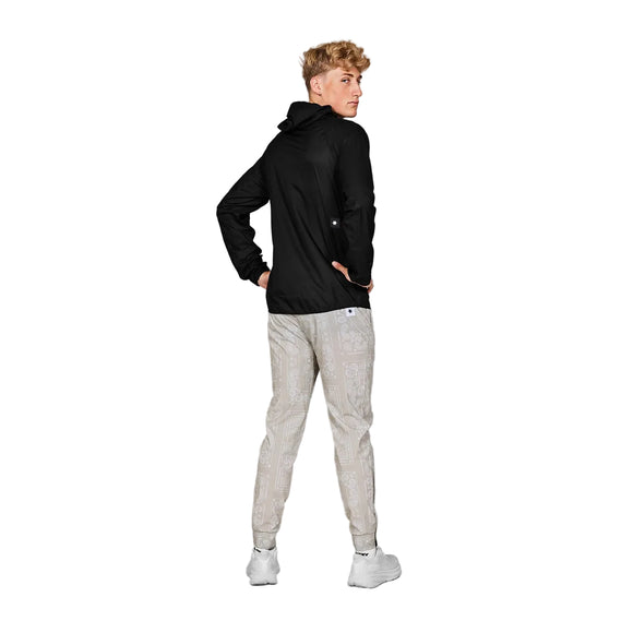 En person vender sig bagud og kigger sig over venstre skulder iført Saysky Flow 2.5L Waterproof Jacket til mænd i sort. Den er sat sammen med letmønstrede bukser og hvide sneakers på en almindelig grå baggrund.