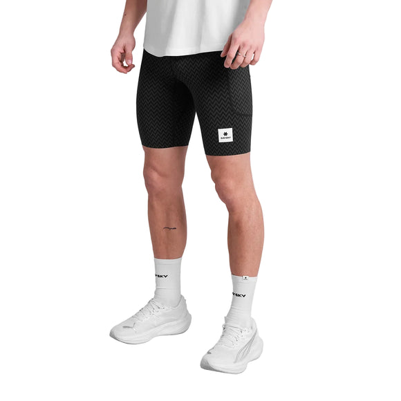 En person er iført en hvid T-shirt, Saysky Zig Zag Combat+ Short Tights 9" Herre in Black Zigzag, hvide strømper med sort tekst og hvide sportssko, mens han står på en almindelig hvid baggrund.
