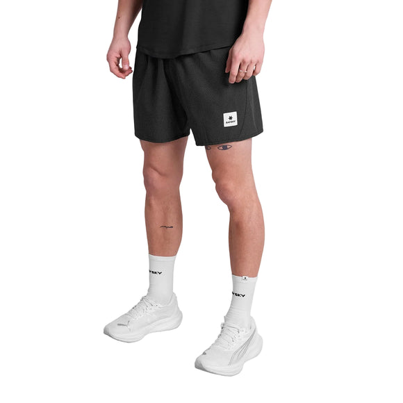 En person i sort t-shirt, Saysky Zig Zag Pace Shorts 5" (Herre, Black Zigzag), hvide tekststrømper og hvide sportssko står på en almindelig hvid baggrund.