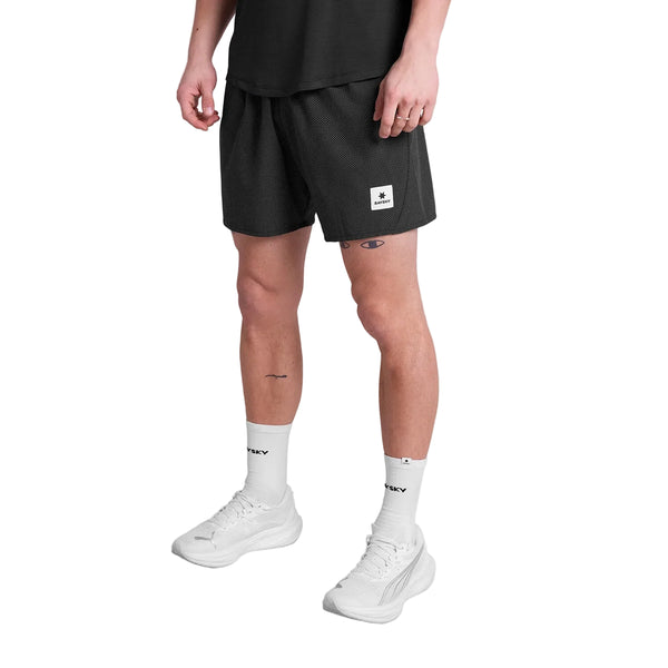En person i sort t-shirt, Saysky Zig Zag Pace Shorts 5" (Herre, Black Zigzag), hvide tekststrømper og hvide sportssko står på en almindelig hvid baggrund.