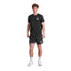 En person står med ansigtet fremad i en sort t-shirt og Saysky Zig Zag Pace Shorts 5", Herre, Black Zigzag, med hvide sokker og sneakers på en hvid baggrund.