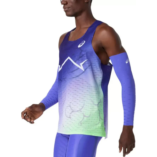 En person er iført Asics Metaspeed Singlet, Herre, Cobalt Burst - en luftig, ærmeløs top i en blå og grøn farve med zigzag-hvide detaljer - sammen med matchende blå ærmer og leggings, vist med taljen op mod en ensfarvet baggrund.