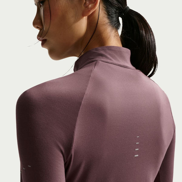 En kvinde med mørkt, tilbagestrøget hår ses bagfra iført en lilla Nike Swift UV Half Zip Running Top til kvinder i Tattoo/Reflective Silver med lange ærmer, høj krave og små refleksdetaljer på ryggen.