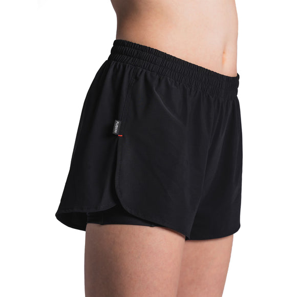 En kvinde er iført Fusion Run Shorts, Dame, Black med elastisk linning og et lille mærke i siden, vist fra taljen til midt på låret mod en almindelig hvid baggrund. Disse åndbare løbeshorts giver komfort til træning.