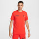 En mand kigger fremad i en pikant rød Nike Dri-FIT løbe-T-shirt til mænd med sorte løbesilhuetter og en hvid Nike-swoosh, sammen med matchende røde shorts på en almindelig hvid baggrund.