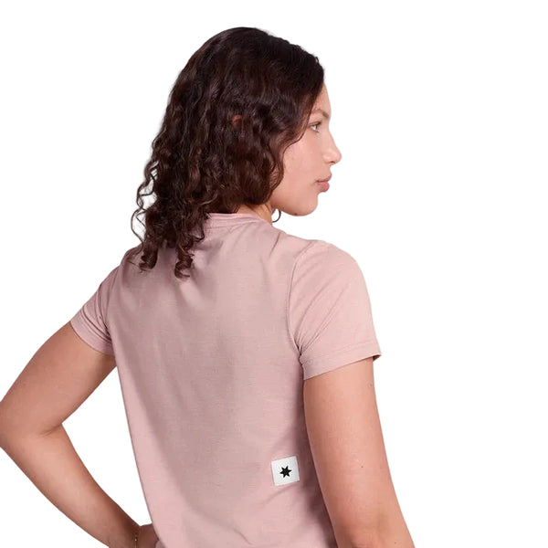 En person med krøllet brunt hår ses bagfra iført en pink Saysky Clean Pace T-shirt til kvinder med et lille hvidt mærke og en sort stjerne nær kanten. Baggrunden er hvid.