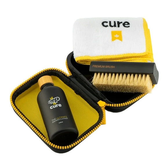 Crep Protect Cure Shoe Cleaning Kit, Unisex fra Crep Protect indeholder en gul og sort lynlåstaske, en Cure-flaske, en børste med træhåndtag og lette børster samt en foldet hvid klud - ideel til at holde dine løbesko pletfri.