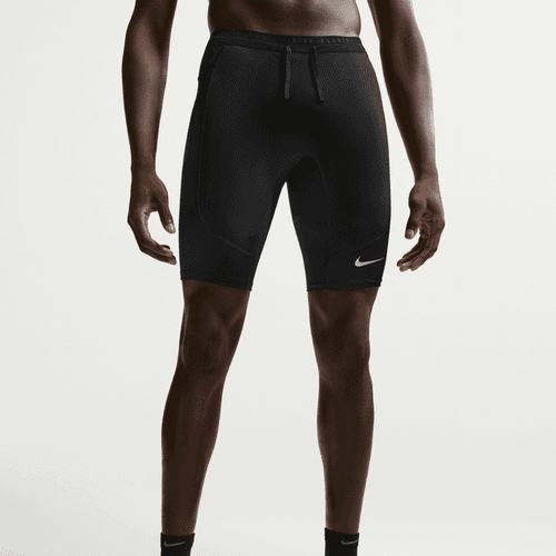 En person er iført Nike Nk Df Stride Half Tight, Herre, Black/Reflective Silv tights med et synligt logo på venstre ben. Kun underkroppen og benene er vist mod en almindelig hvid baggrund, hvilket fremhæver disse fugttransporterende tights.