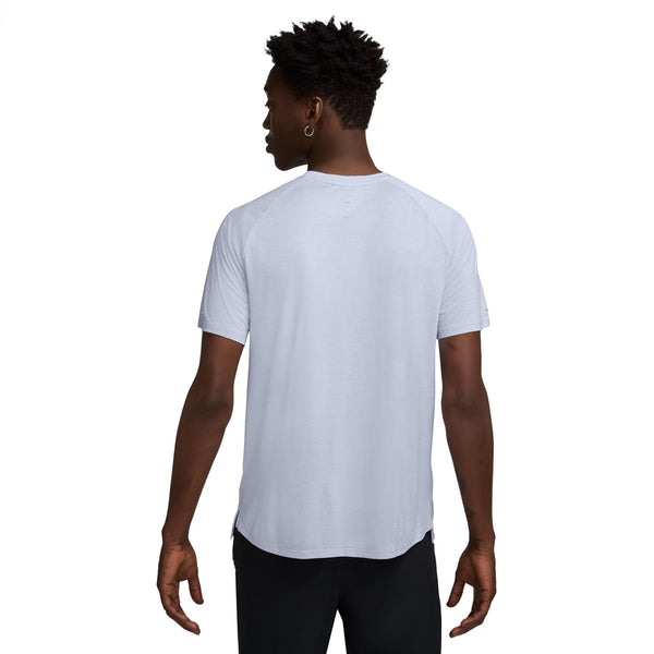 En person kigger væk fra kameraet iført en Nike Dri-FIT ADV kortærmet løbetop til mænd i Ghost/Htr/Reflective Silver og sorte bukser på en almindelig hvid baggrund.