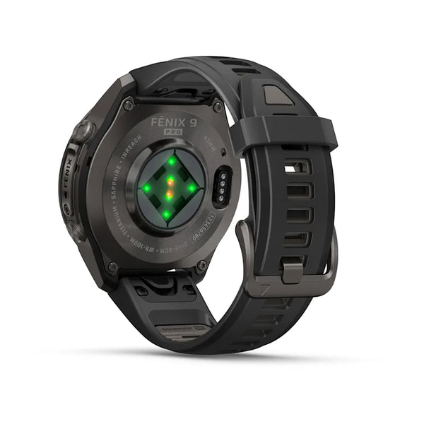 Et Garmin fenix 9 Pro InReach 43 mm AMOLED-smartur i Carbon Grey DLC-titanium med sort rem vises set bagfra, hvor man kan se de grønne sensorlamper og en opladningsport. Urets elegante sorte rem har en sikker lås og flere justeringshuller, hvilket er et eksempel på Garmins avancerede teknologi – ideelt til eventyrere, der ønsker banebrydende InReach-satellitforbindelse.