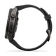 Et sort Garmin fenix 9 Pro InReach 43 mm AMOLED-smartur ses set fra siden, hvor dets runde urskive, to knapper og remmen med spænde ses tydeligt. Det robuste og slidstærke urhus i carbon-gråt DLC-titanium har navnet »fenix« indgraveret ved siden af knapperne, hvilket understreger, at dette er den avancerede Garmin fenix 9 Pro-model i farven Black/Pebble.
