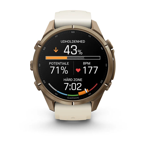Garmin fenix 9 Pro inReach AMOLED 43 mm, der har en ramme i farven Autumn Gold Titanium med et silikonerem i farverne Cream/French Grey, er et multisport-smartur med en rund AMOLED-skærm. Skærmen, der vises på dansk, viser udholdenhed på 43 %, potentiale på 71 %, puls på 177 og klokkeslættet 7:02 sammen med forskellige farvede fremskridtsbjælker. Denne avancerede enhed har også integrerede inReach-satellitfunktioner, der giver øget sikkerhed under dine eventyr.
