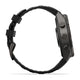 Set fra siden: Garmin fenix 9 Pro inReach 47 mm med en kulgrå DLC-titaniumkasse og et sort og småstengråt silikonerem. Det robuste multisport-smartur har to runde trykknapper og en struktureret rem. Selvom urskiven ikke er synlig, signalerer dets robuste design holdbarhed – hvilket gør det perfekt til udendørs eventyr eller sportsaktiviteter.