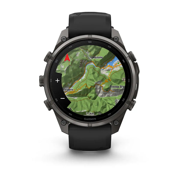 Et Garmin fenix 9 Pro inReach 47 mm smartwatch i Carbon Grey DLC-titanium med et sort/stengråt silikonerem viser et topografisk kort med højdekurver, en rød kompasspil og stednavne som f.eks. Luvinonec og Treviso Brec. Uret har fire sideknapper.