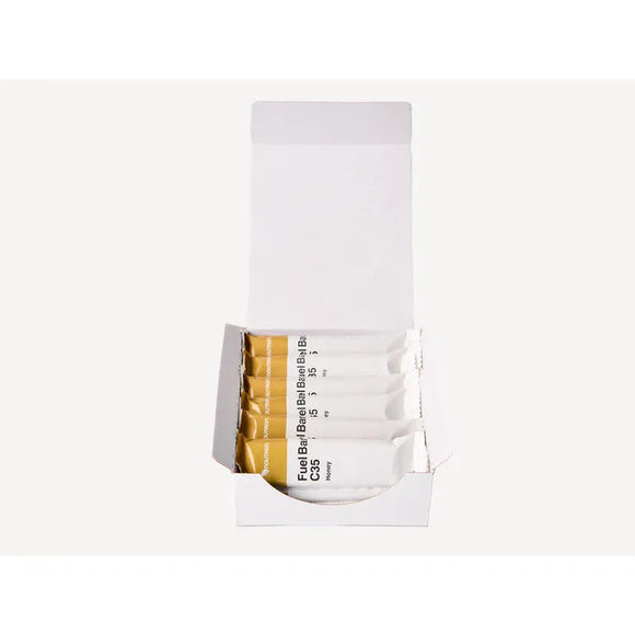 En åben hvid æske med Noutron Fuel Bar Honey Kasse - 12 stk. viser flere opretstående, individuelt indpakkede barer med delvist synlig tekst på indpakningen. Baggrunden er helt hvid.