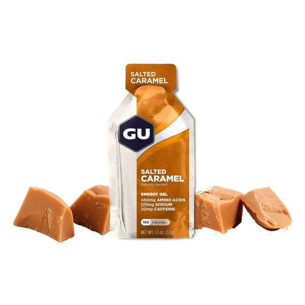 En GU Energy Gel, Salted Caramel fra GU Energy står oprejst med fire karamelbolsjer. Hver gel indeholder 100 kalorier, 450 mg aminosyrer, 125 mg natrium og 20 mg koffein, som giver hurtig energi.