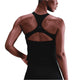 En kvinde iført en Nike Outdoor Bra Tank i Black/Summit White ses bagfra med venstre hånd hvilende på hoften mod en hvid baggrund.
