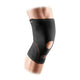 En person bærer McDavid Knee Support w/open patella, Unisex, Black, med røde syninger på sit bøjede knæ mod en hvid baggrund.
