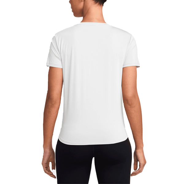 En kvinde kigger væk fra kameraet i en Nike Dri-Fit Short-Sleeve Top, Dame, White/Black, sammen med sorte bukser. Baggrunden er helt hvid.