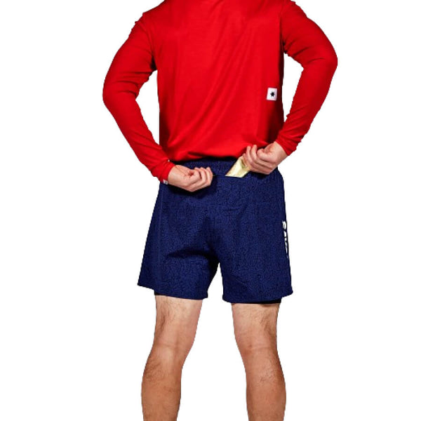 En person i rød langærmet skjorte og Saysky CC Pace 2 in 1 Shorts 5", Herre, Blue ses bagfra lægge en foldet pengeseddel i shortsens baglomme.