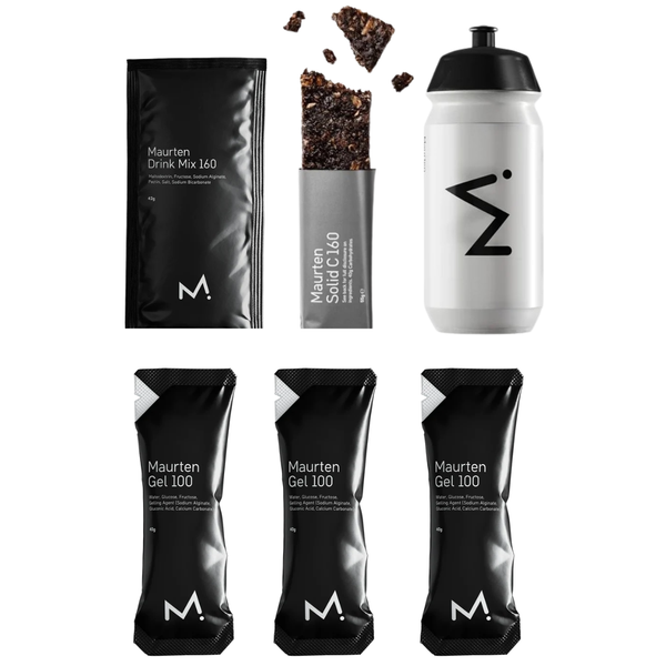 Seks Maurten-produkter fra Maurten Race Pakke – herunder en SOLID 160-bar, der er skåret over, en Drink Mix 160-pose, en vandflaske og tre GEL 100-poser – er afbildet på en hvid baggrund. Emballagen har et minimalistisk design i sort med hvid tekst.