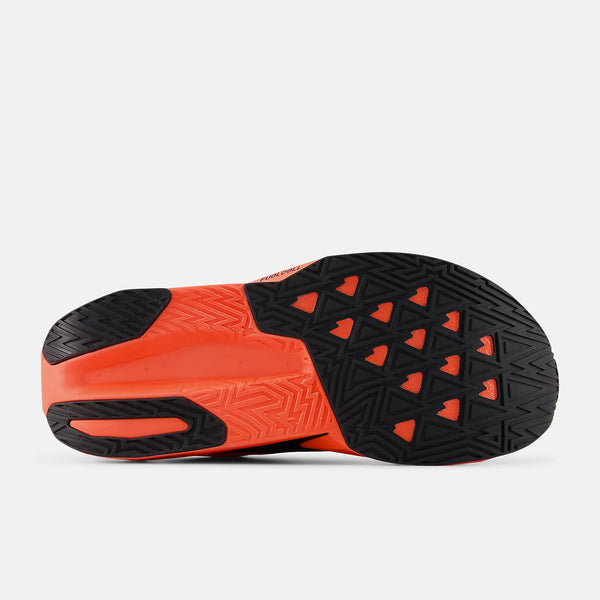 Billedet viser sålen på New Balance FuelCell Rebel V5 Dame i Urgent Red/Black/Silver Metallic, der har et struktureret mønster med trekantede former og zigzag-riller for bedre greb.