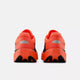 Et par New Balance FuelCell Rebel V5 dame løbesko i Urgent Red/Black/Silver Metallic vises bagfra på en hvid baggrund, der fremhæver hælen, ydersålen og de reflekterende sølvfarvede detaljer.