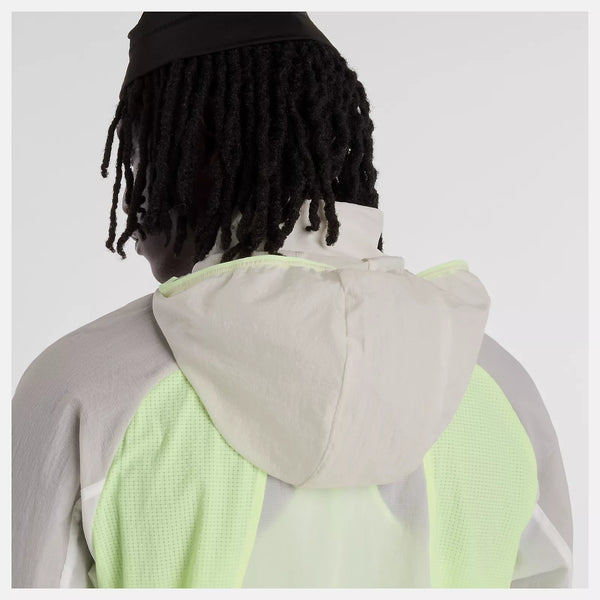 En person med mellemlange dreadlocks, set bagfra mod en hvid baggrund, er iført en lys New Balance Rc Jacket, Herre, Afterglow - en ideel stilfuld og funktionel løbejakke herre med neongrønne meshpaneler.