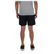 En person kigger væk fra kameraet iført en lysegrå T-shirt og New Balance AC Lined Shorts 7", Herre, Black. De har også sorte sportssko på, med en almindelig hvid baggrund.