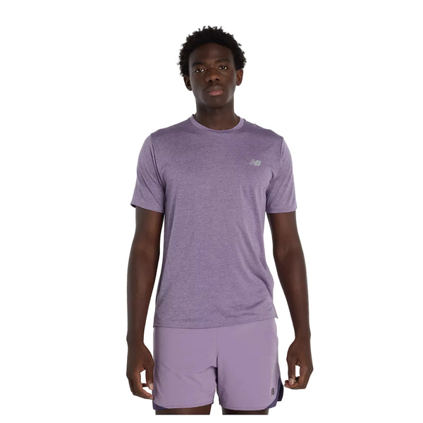 En person ser frem for sig iført en New Balance Athletics T-shirt til mænd i Candied Violet Heather med matchende shorts på en almindelig hvid baggrund.