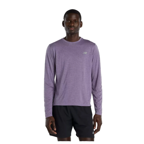 En person står og kigger fremad iført en New Balance Athletics Long Sleeve, Herre, Candied Violet Heather med et lille logo på brystet og sorte shorts. Baggrunden er almindelig hvid.