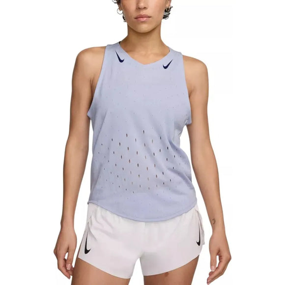 En kvinde er iført en lysegrå Nike AeroSwift Running Singlet (Dame, Ghost/Blue Void) med diskrete ventilationshuller og hvide shorts, begge med Nike-logoer. Hun står med armene afslappet langs siden.