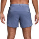 En person vises fra taljen og ned iført Nike Dri-FIT 5" Stride Running Shorts til mænd i World Indigo/Black/Reflective Silv, med ryggen og benene synlige.