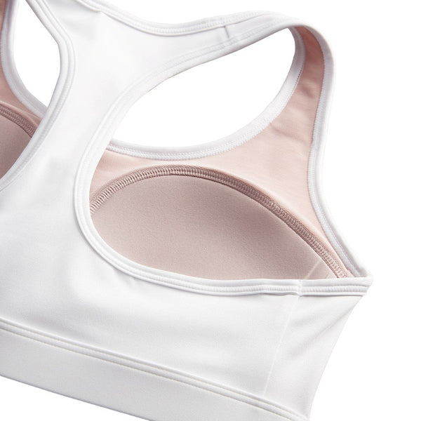 Nærbillede af Nike Swoosh Medium Sports Bra til kvinder i White/Stone Mauve/Black med medium støtte, racerback-design, lyserødt inderfor og blødt Dri-FIT-materiale. Bh'en ligger fladt på en hvid baggrund.