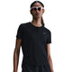 En kvinde med langt tilbagestrøget hår bærer en sort Nike Dri-FIT Short-Sleeve Running Top, Dame, Black/Reflective Silv og mørke solbriller, mens hun står på en almindelig hvid baggrund. Toppen har et lille reflekterende Nike-logo på brystet.