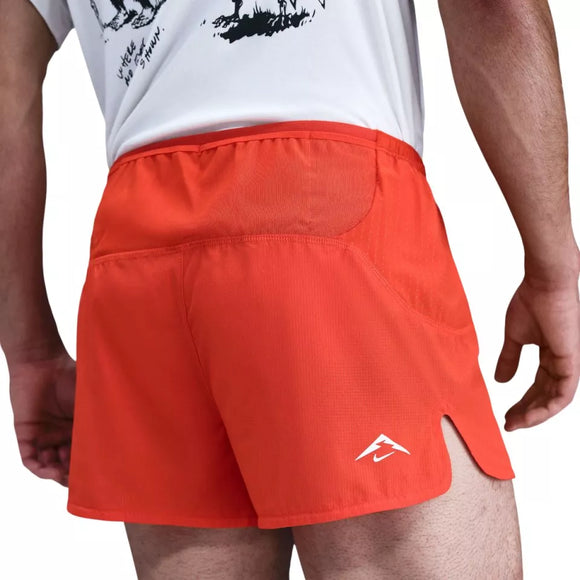 En person iført Nike Trailwind 3" Shorts, Herre, i Picante Red/Black med Dri-FIT-teknologi står med ryggen til kameraet; en hvid grafisk t-shirt ses også-perfekt til trailløb eller hverdagskomfort.