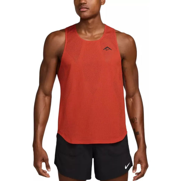 En mand i en Nike Dri-FIT ADV Running Singlet (Herre, Picante Red/Red Sepia/Htr/Black) med et lille logo på brystet og sorte shorts med et hvidt Nike-logo står med front mod en almindelig baggrund. Perfekt som Nike løbetøj.