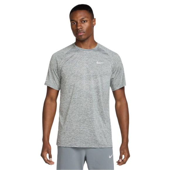 En mand kigger fremad i en Nike Stride ADV kortærmet løbetop, Herre, Smoke Grey/Htr/Reflective Silver, og matchende grå Dri-FIT ADV shorts. Begge har Nike-logoet og er placeret på en almindelig hvid baggrund.
