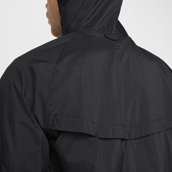 Et nærbillede af en person iført Nike Nk Rpl Jakob Jkt til herrer i Black/Black/Metallic Gold, der viser ryggen og en del af ansigtet. Det lette materiale har Dri-FIT-teknologi for ekstra komfort.