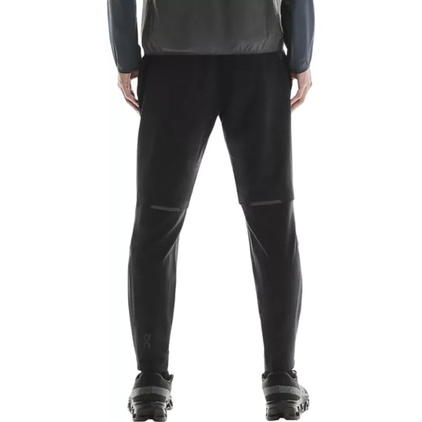 En mand ses bagfra, stående oprejst og iført en mørk jakke, sorte løbesko og On Weather Winter Pants, Herre, Black. Billedet er beskåret ved overkroppen.