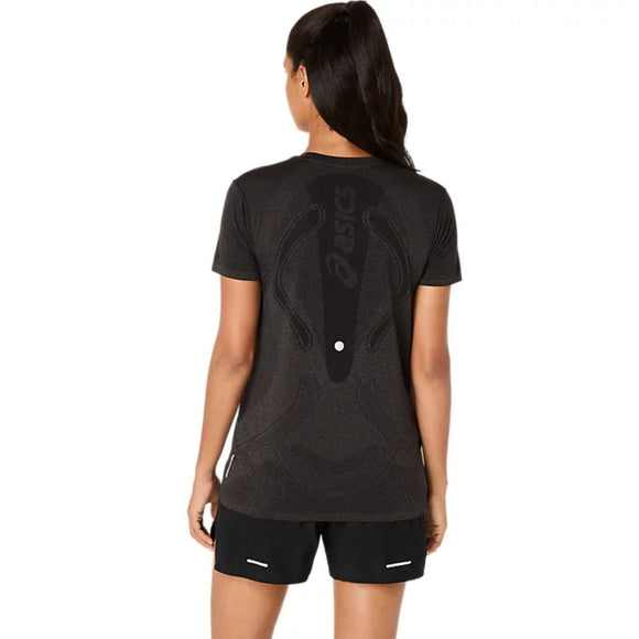 En kvinde med hestehale står med ryggen til kameraet iført Asics Road Seamless SS Top til kvinder i Performance Black/Graphite Grey og sorte løbeshorts mod en enkel hvid baggrund.