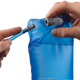 Et par hænder forbinder en blå Salomon Soft Reservoir 1,5L (Unisex, Clear Blue) slange med mundstykkets åbning. Dette fleksible reservoir, der er perfekt til vandreture, har tydelige målemarkeringer på forsiden.