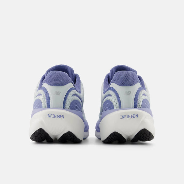 En bagside af New Balance Infinion 1080 v15 dame løbesko i Glint Blue/Silver Metallic/Fairweather Blue med "NB" og "Infinion 1080 v15" på hælene, designet til maksimal komfort, sat mod en almindelig hvid baggrund.