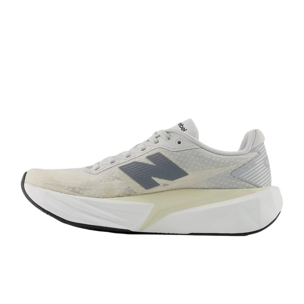 Et sidebillede af New Balance Fuelcell Rebel V5 løbesko dame i Linen/Grey Matter med en chunky hvid sål for optimal energireturnering, et mørkegråt N-logo, sort ydersål og subtil mesh-struktur på overdelen.