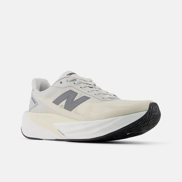 New Balance Fuelcell Rebel V5 Dame i Linen/Grey Matter har en tyk hvid sål, sort ydersål og et fedt mørkegråt N-logo, der er designet til overlegen energireturnering. Vist mod en almindelig hvid baggrund.