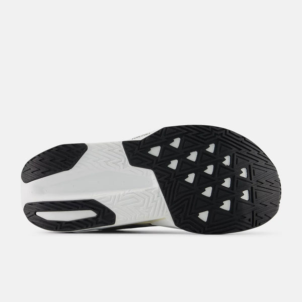 Billedet viser sålen på New Balance Fuelcell Rebel V5, Dame, Linen/Grey Matter med en sort og hvid geometrisk slidbane med trekanter og zigzag-linjer, der giver greb, støtte og optimal energireturnering.