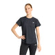 En person står og kigger fremad iført en grå New Balance Race Day Ultra Light T-Shirt, Dame, med NB ICEx-teknologi og matchende sorte leggings med New Balance-logo på en almindelig hvid baggrund.