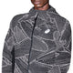 En mand er iført ASICS Limited Series Lite-Show Jacket, Herre, Performance Black, med geometrisk hvidt mønster, hætte, refleks-teknologi og logo på brystet. Billedet er beskåret under næsen med hovedet delvist ude af billedet.